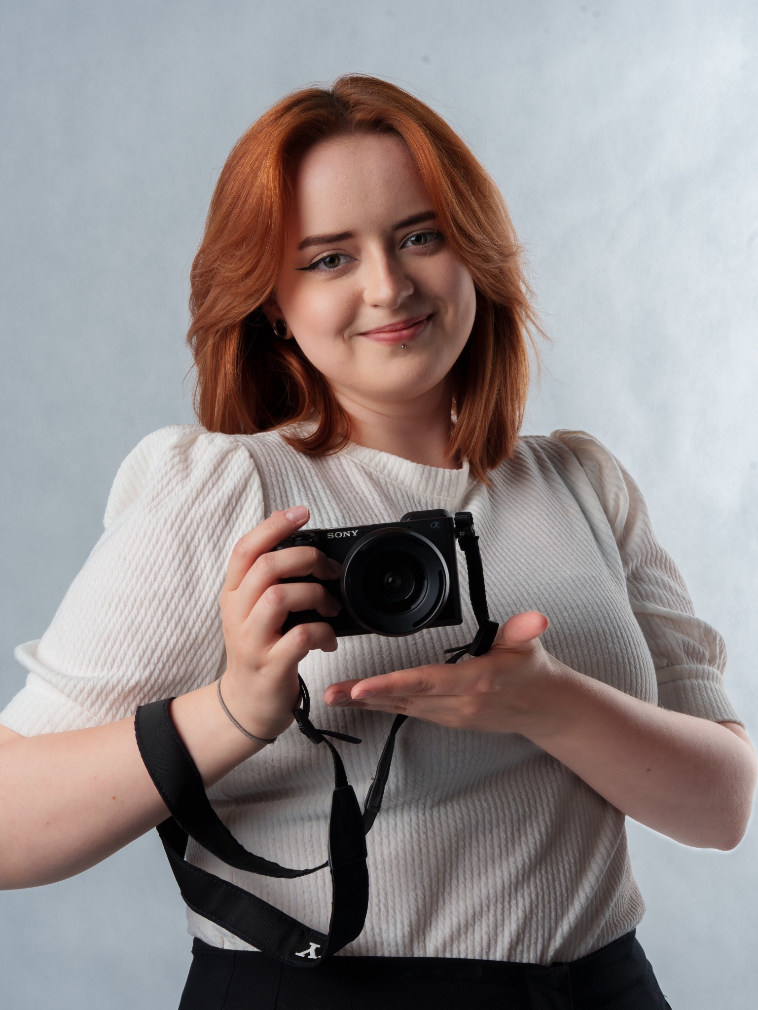 Portret rudowłosej kobiety trzymającej aparat fotograficzny