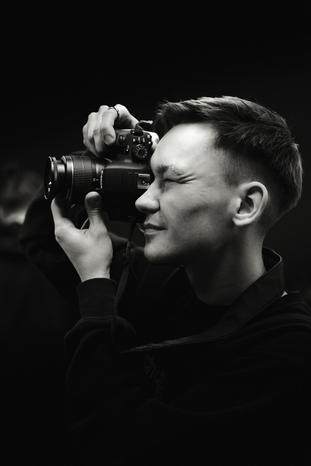 Czarno-biały portret mężczyzny fotografującego aparatem